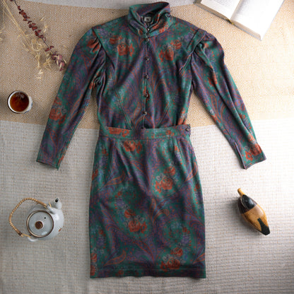 Vintage Ungaro Parallèle Paris 80s Two-Piece Skirt Suit – emerald green, rust and mauve paisley floral jersey, high neck blouse with jewel button-front and dramatic puff shoulders, long sleeves, matching high-waist pencil midi skirt, Made in Italy, flat lay editorial shot