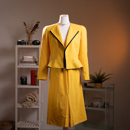 Archival Louis Féraud Paris NOS Deadstock 80s Power Suit – canary yellow two-piece skirt suit with structured strong-shoulder cropped blazer, black contrast lapel trim and single gold button, matching midi pencil skirt with front kick pleat, Made in West Germany, product shot on dress form