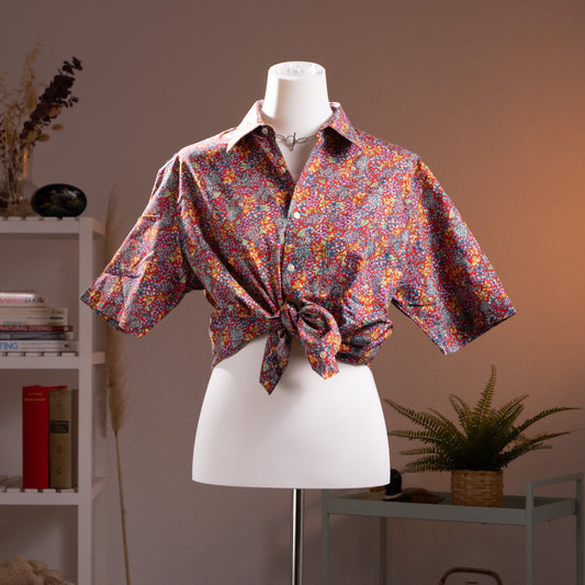 Archival Nina Ricci NOS Deadstock 90s Floral Print Shirt – dense Liberty-style ditsy floral print in red, pink, purple, yellow and teal on cotton, point collar, short sleeves, button-front, shown knotted at waist in dandy androgynous style, museum quality, product shot on dress form