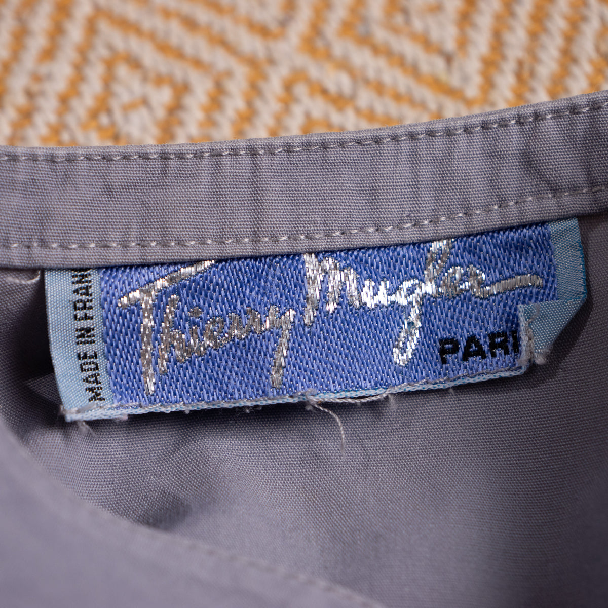 Close-up of the crisp vintage Thierry Mugler Paris woven mainline script inner neck label in vault preservation quality.
