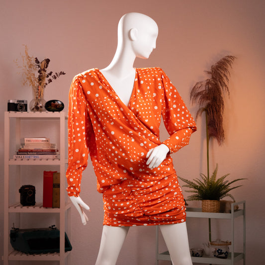 Front view of the archival Emanuel Ungaro Parallèle orange silk polka dot draped wrap dress from the late 1980s on a museum mannequin.