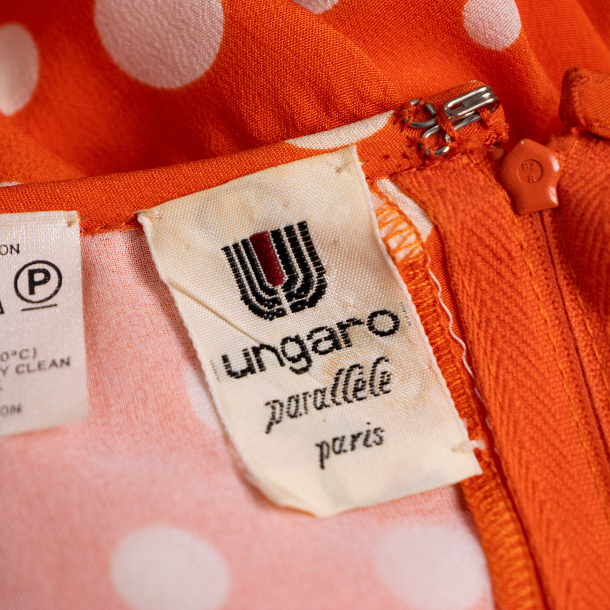 Close-up interior view of the woven white Emanuel Ungaro Parallèle Paris main brand label near the color-matched zipper tracking.