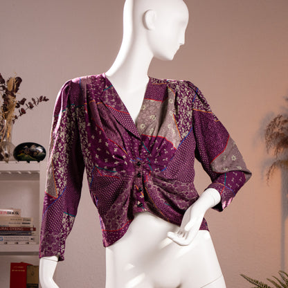 Front view of the flawless archival Emanuel Ungaro Parallèle patchwork print silk jacquard blouse highlighting the draped V-neckline and faceted black buttons on a museum mannequin.
