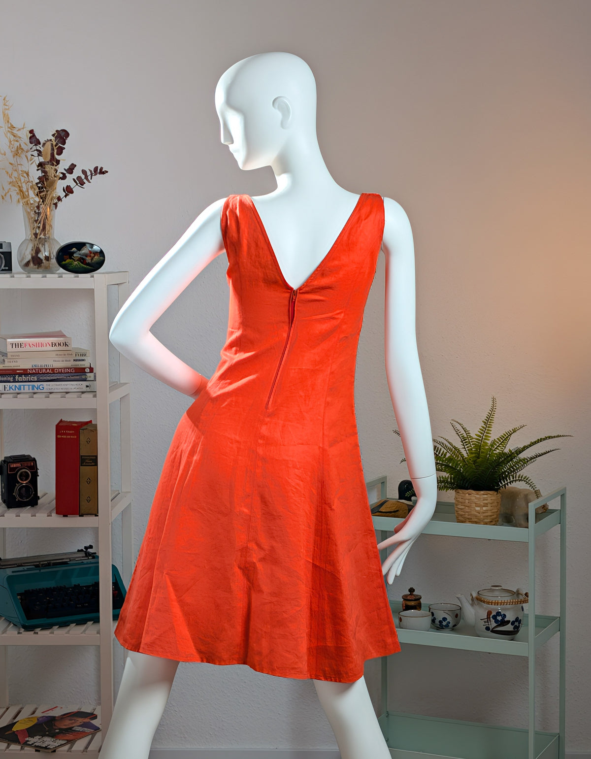 Back view of the 1993 Gianni Versace linen runway dress worn by Emma Sjöberg on the mannequin. The reverse features a deep V-neckline leading into a perfectly color-matched, concealed zipper along the center back seam. The tailored construction highlights a clean A-line silhouette, showcasing the premium fabric texture and precise Milanese atelier craftsmanship under studio lighting.