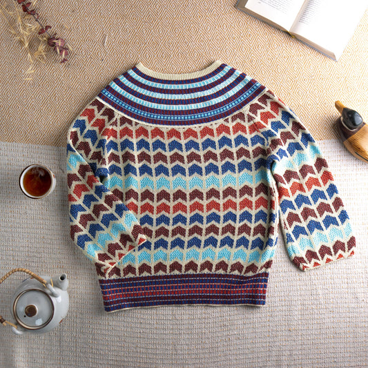 Archival 90s Chevron Lurex Metallic Knit Sweater – cream base with all-over zig zag chevron intarsia pattern in cobalt blue, rust red, chocolate brown and sky blue lurex metallic yarn, striped ribbed crew neck and hem, long sleeves, disco glamour editorial vintage, flat lay editorial shot