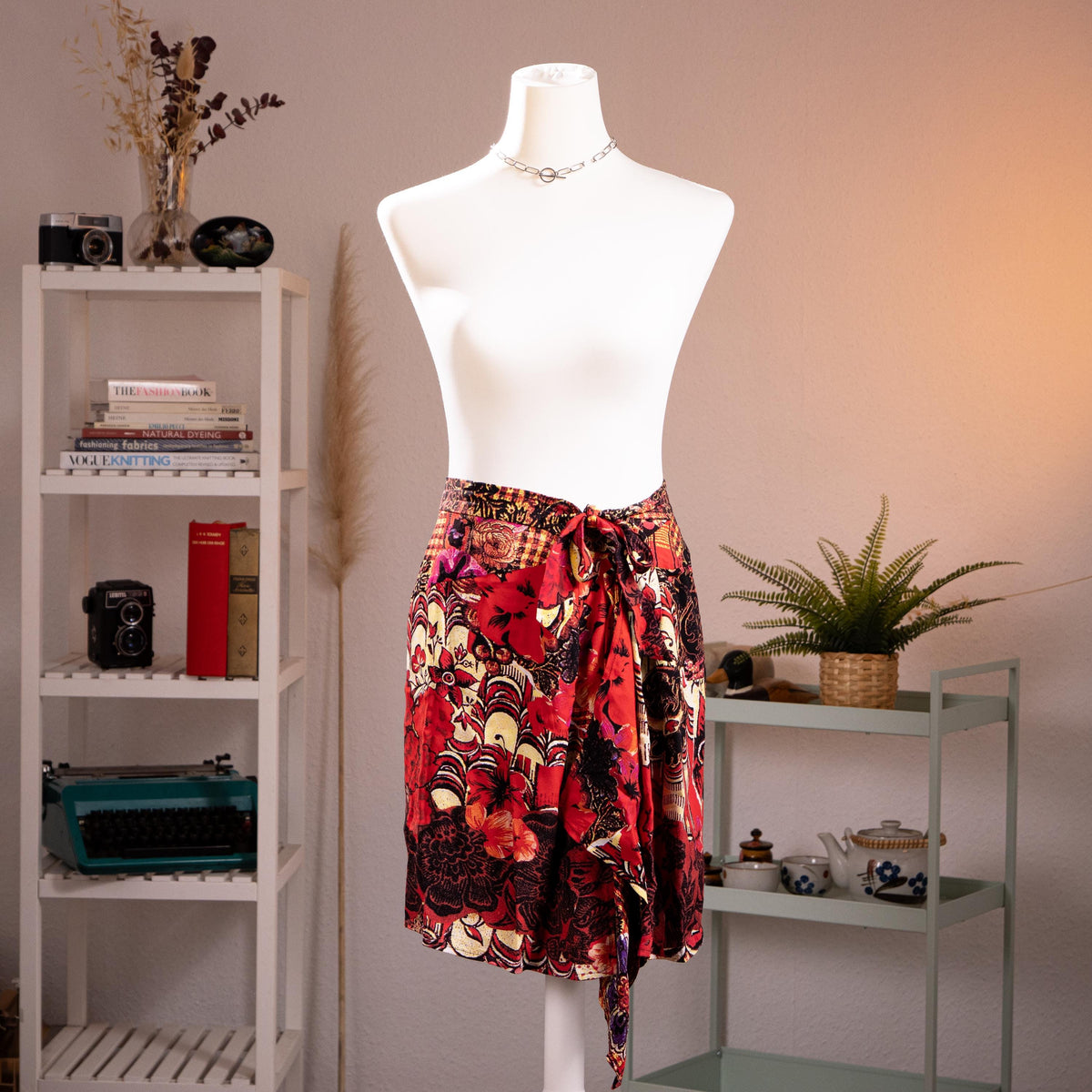 back view Archival Christian Lacroix FW96 Deadstock Asymmetric Wrap Skirt – bold maximalist floral print in crimson red, black, gold and purple on silk-feel fabric, self-tie bow waist, dramatic asymmetric handkerchief hem, product shot on dress form
