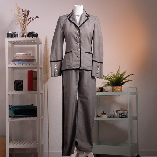 Archival Rena Lange RED 90s Virgin Wool Houndstooth Suit – silver grey fine virgin wool houndstooth blazer and wide-leg flared trousers set, notch lapel with black velvet piping trim, four silver coin buttons front, two piped flap pockets, wide turn-back cuffs with coin button detail, high-waist wide-leg trousers, Falber Italy, product shot on dress form